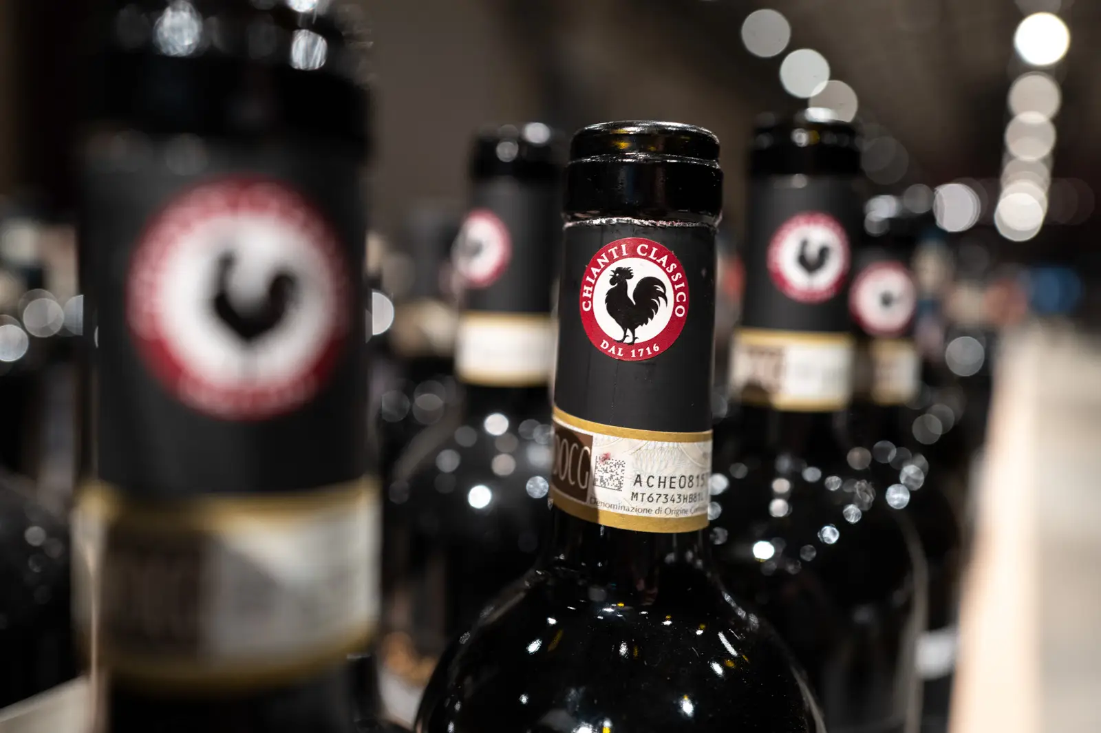 A bottle of Chianti Classico on a restaurant table next to two partially filled red wine glasses and a plate of pasta