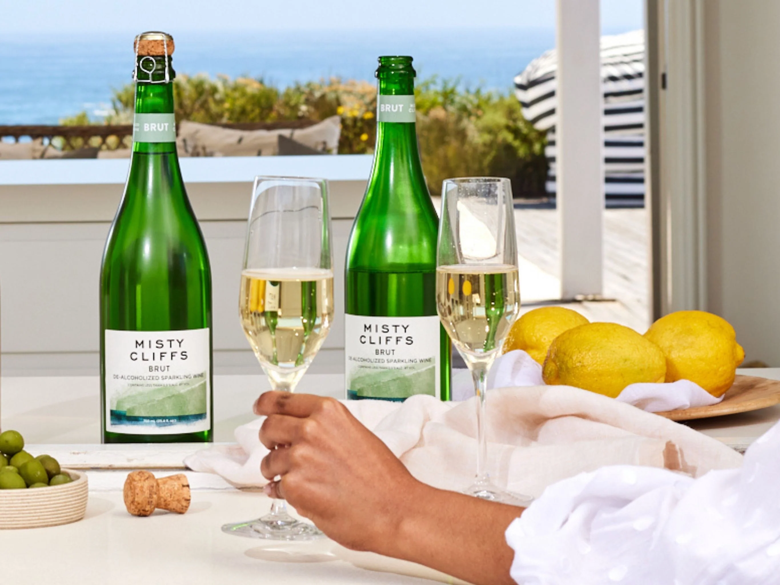 A person pouring nonalcoholic sparkling wine into a flute at a dinner table with plates of food in the background